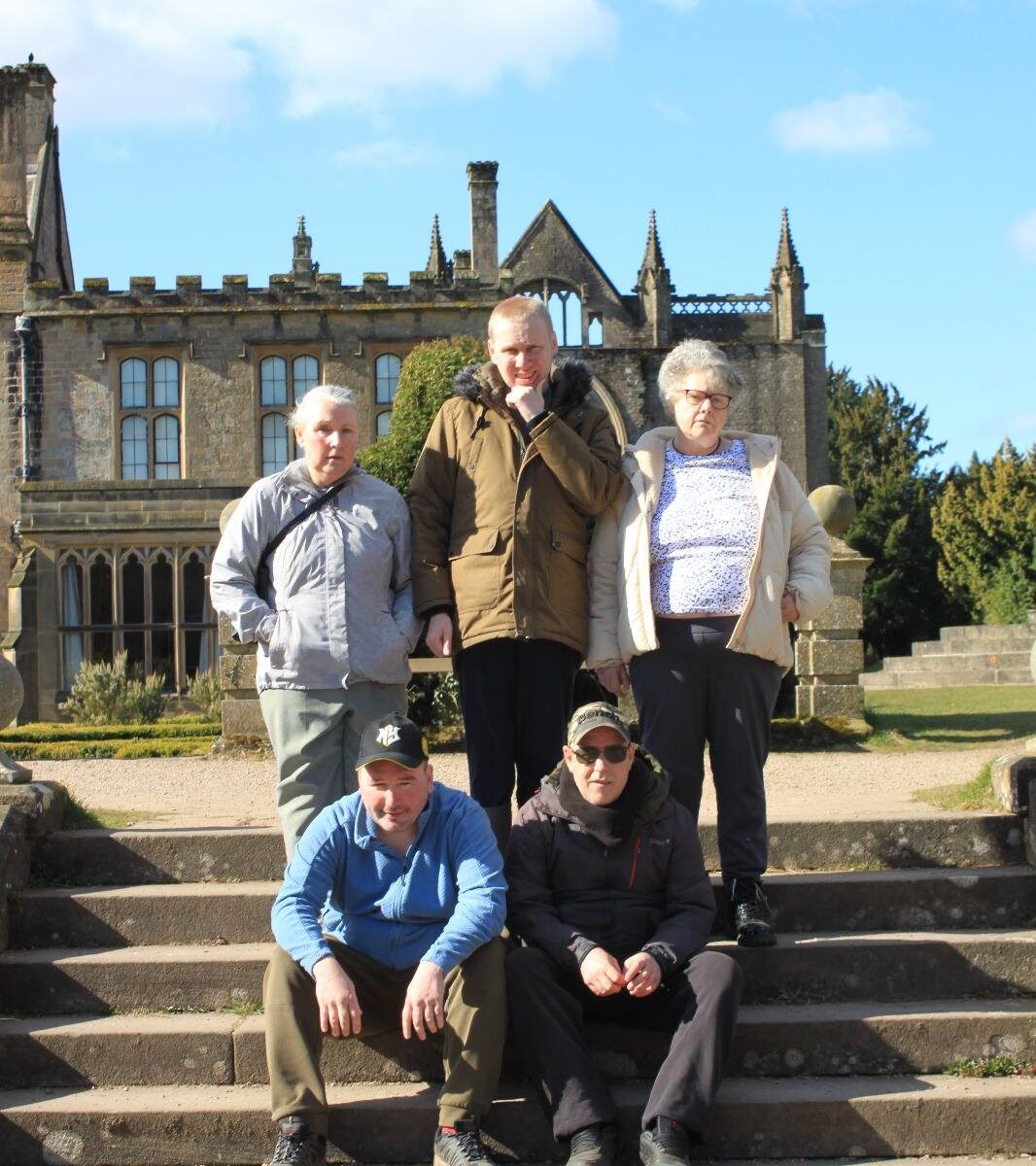 Group standing on a sunny path: "Six members of the Walking Club standing together outdoors, enjoying the sunny weather at Newstead Abbey."