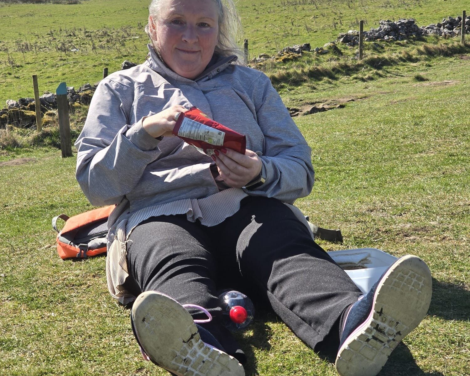 A walking club member sat on the grass eating her packed lunch.