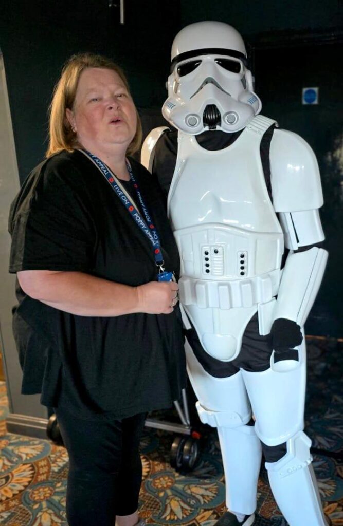 Stormtrooper posing with a smiling woman wearing a lanyard at the event.