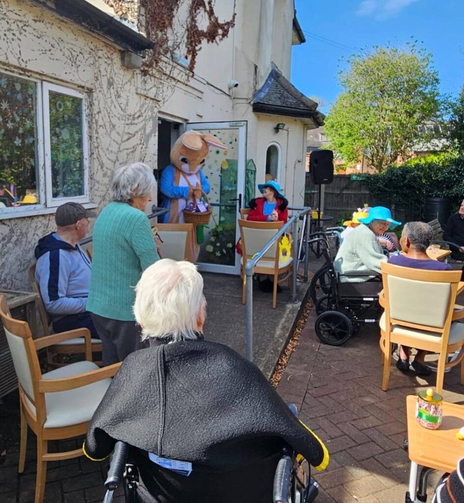 The care home courtyard filled with residents enjoying the sunshine and watching the Easter Bunny hand out treats.